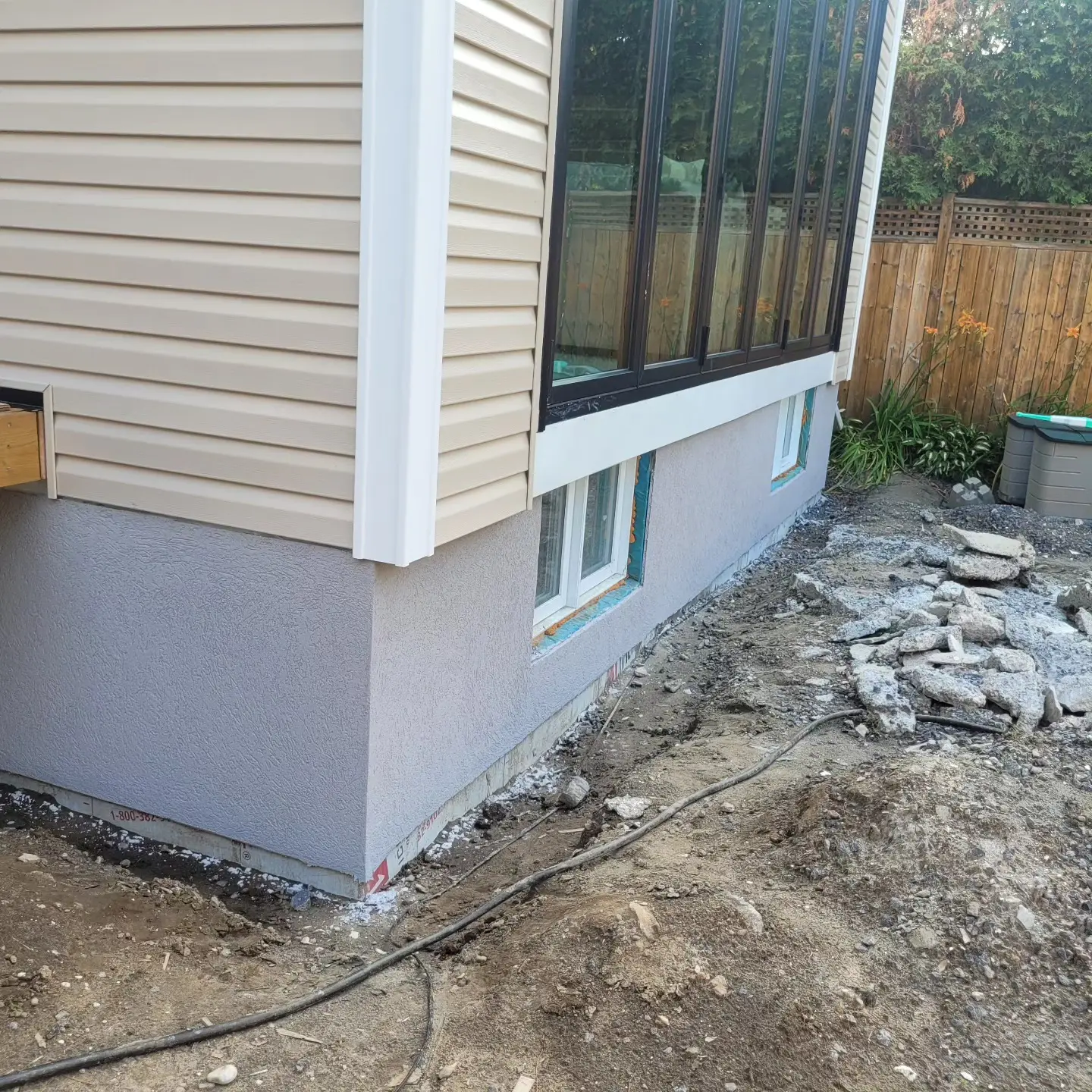 Freshly finished grey parging along a residential foundation